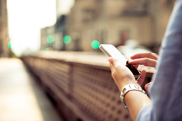 Casual woman typing on the smartphone in the city.